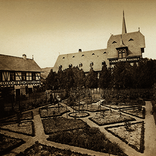 Westansicht des Gutshauses nach dem ersten Erweiterungsbau mit Nebengebäuden und Ziergarten (1879)